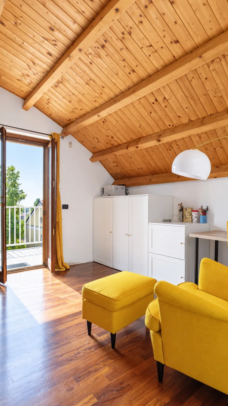 Lo studio: il soffitto in legno, la poltrona e il pouf gialli, la portafinestra aperta sul terrazzo